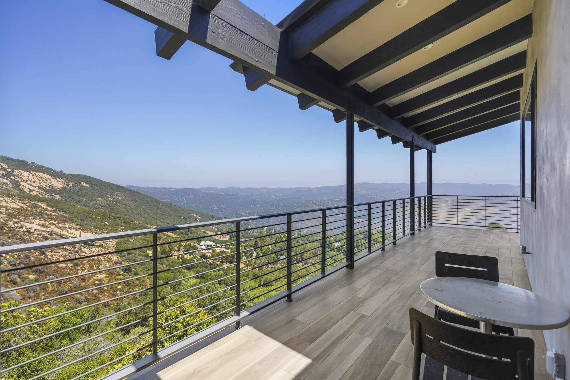 Covered balcony with modern railing overlooking rolling canyon views