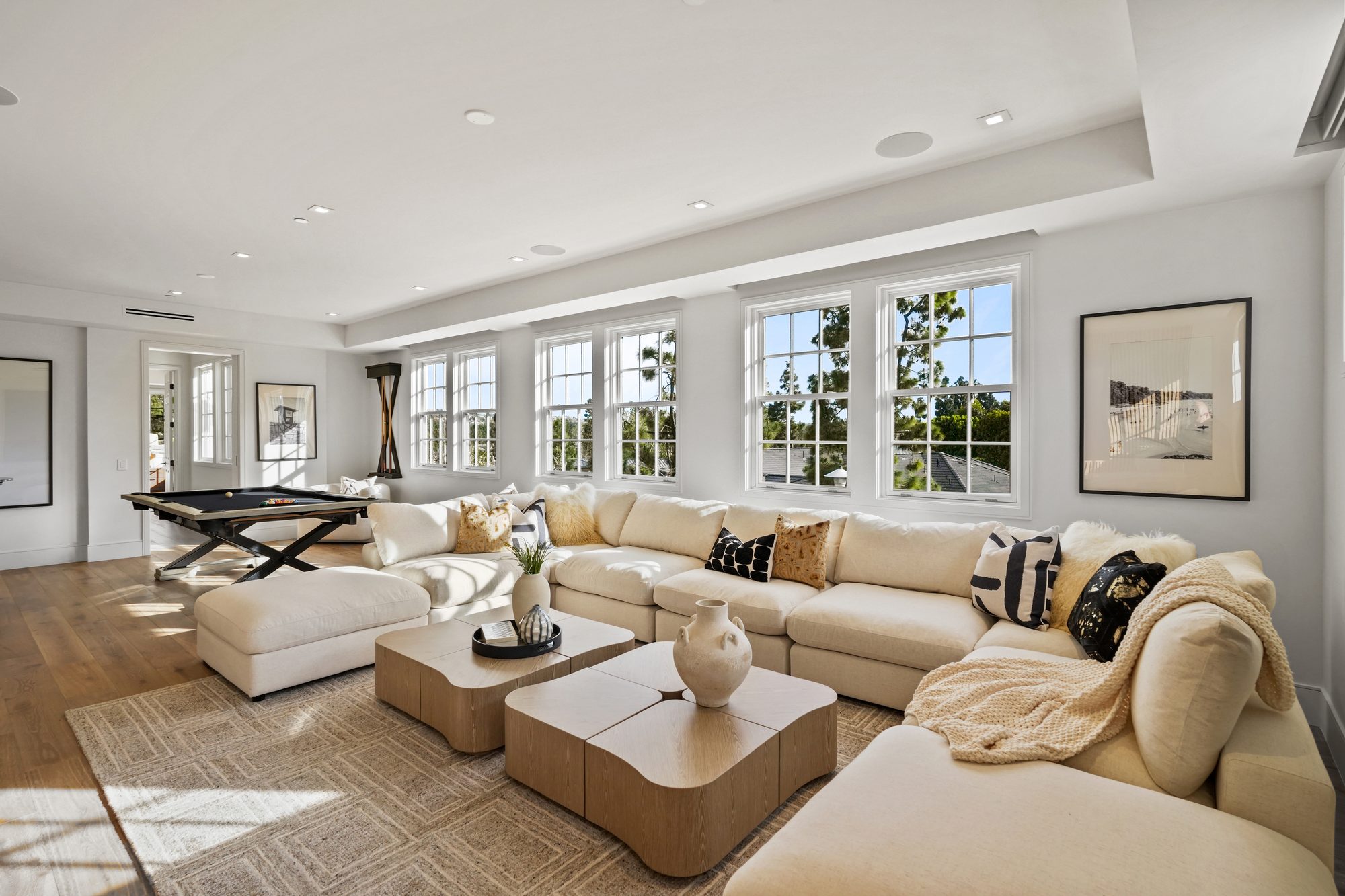Sunlit bonus room with oversized sectional, sculptural coffee tables and pool table