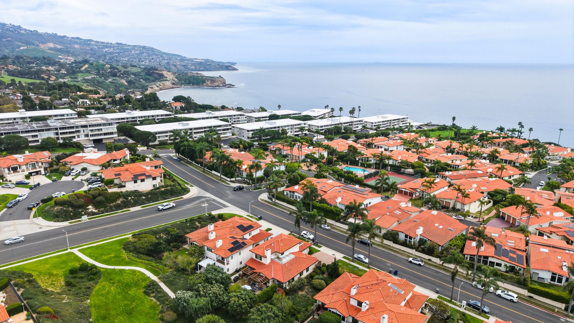 Aerial view of a coastal neighborhood with ocean cliffs and the Pacific in the distance