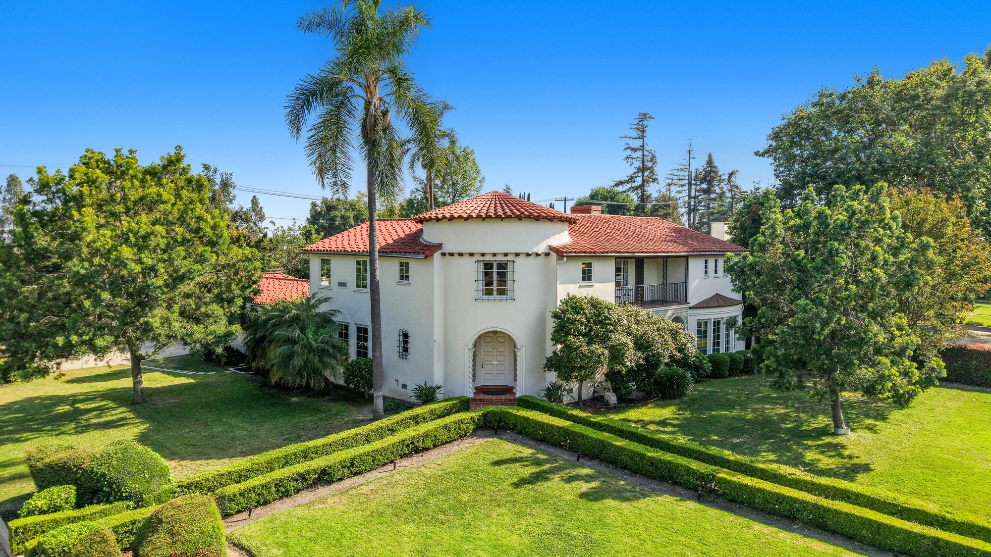 Aerial view of a Spanish Colonial estate with clay tile roof and manicured hedges