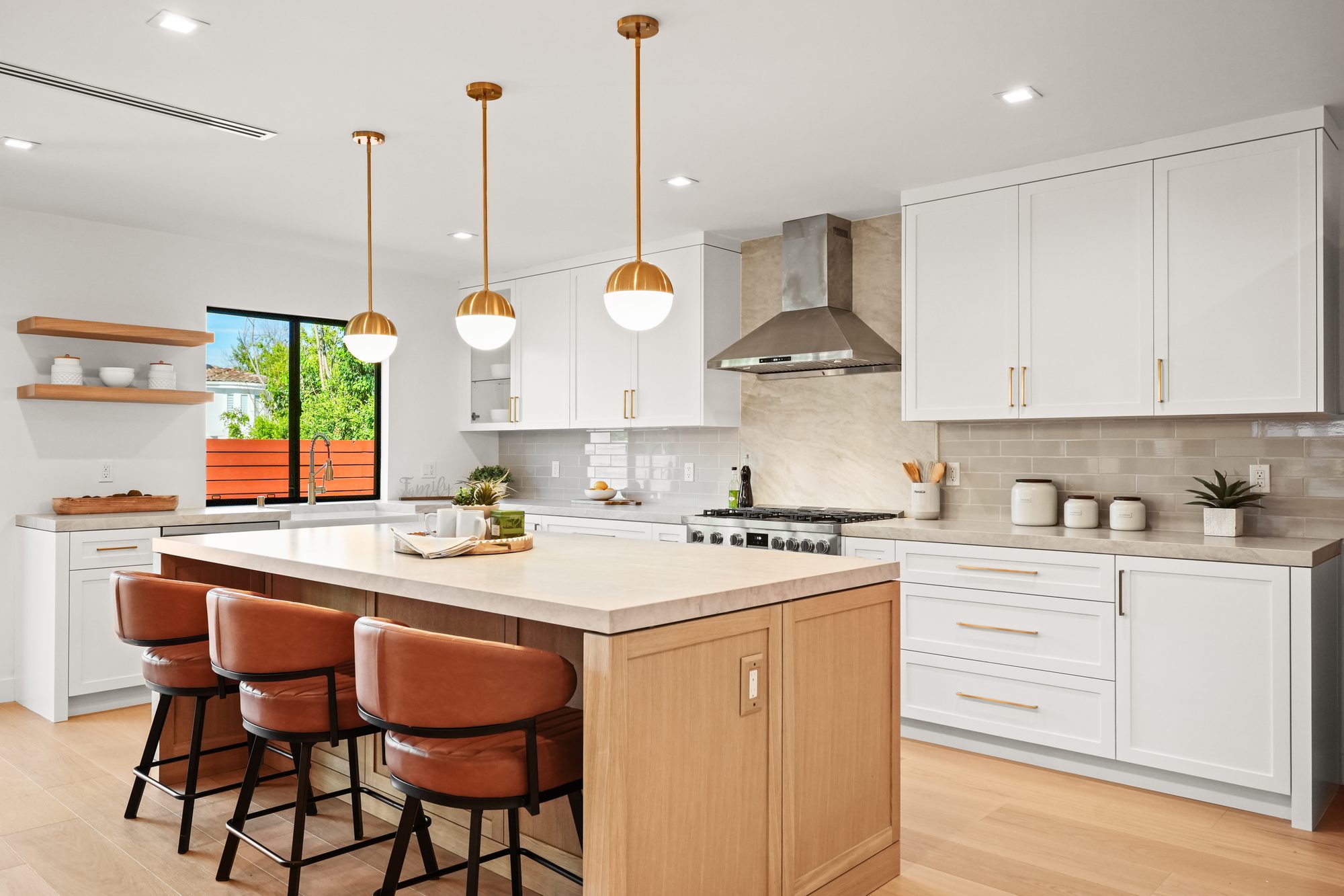 Bright kitchen with oak island, leather stools and gold globe pendants