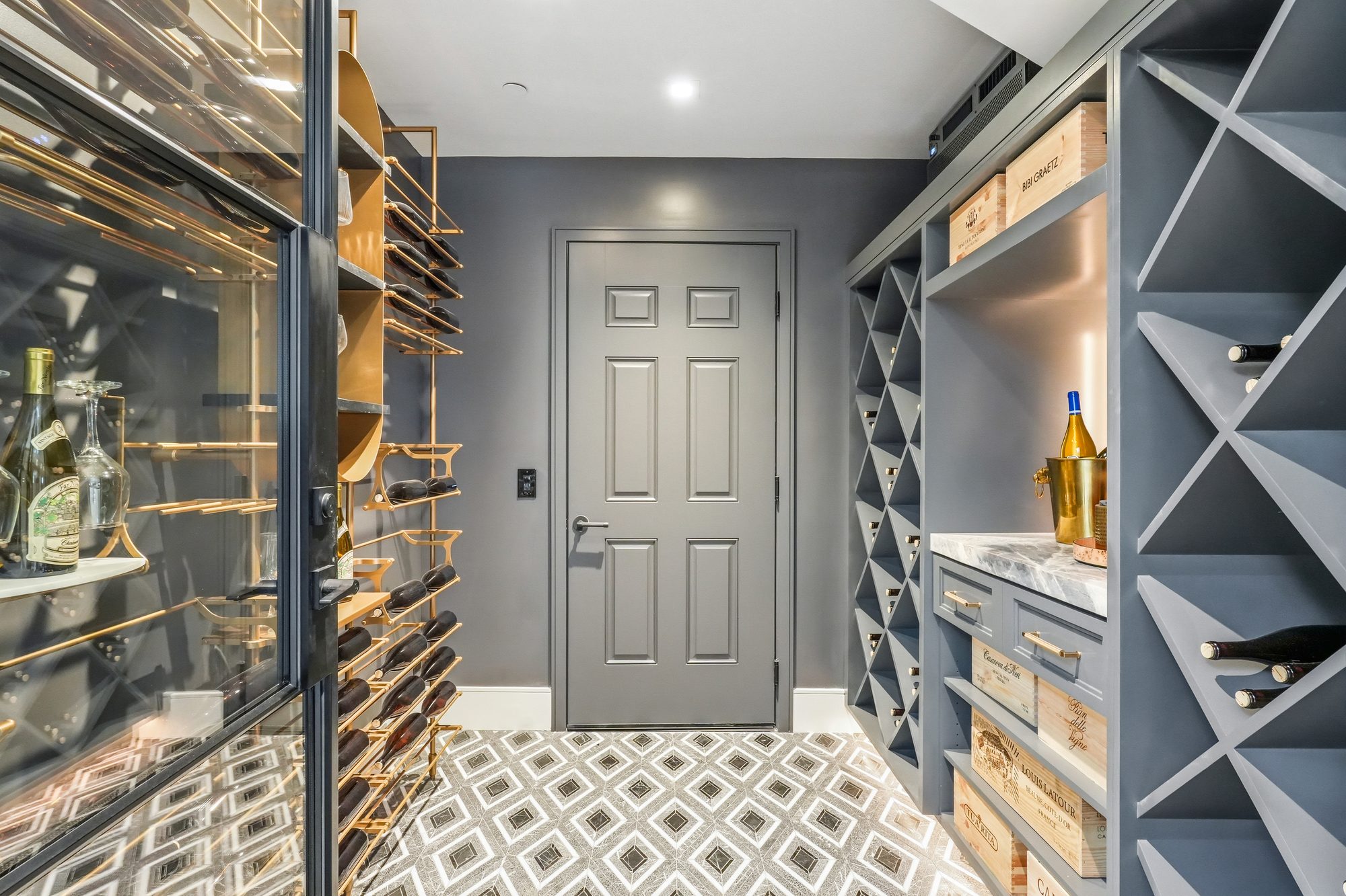 Custom wine cellar with brass racks, glass door and geometric marble floor
